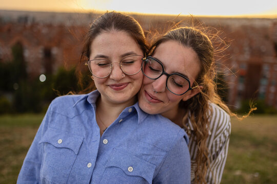 Two women friends hugging outdoors in Madrid at sunset