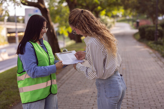 Women signing clipboard outdoors with safety volunteer support
