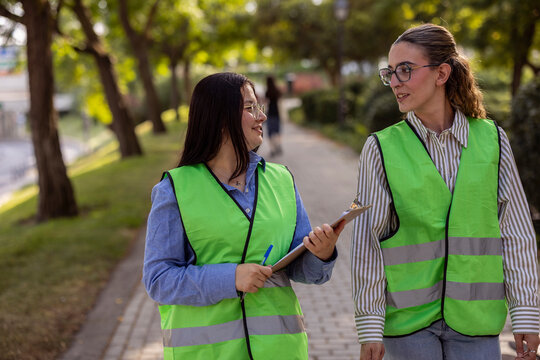 Women in reflective vests talking during outdoor park walk