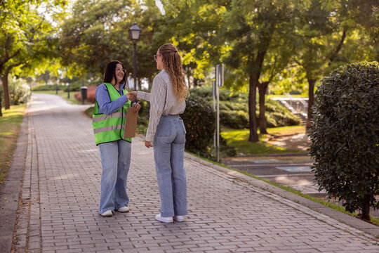 Two women volunteer coordinator with clipboard in park