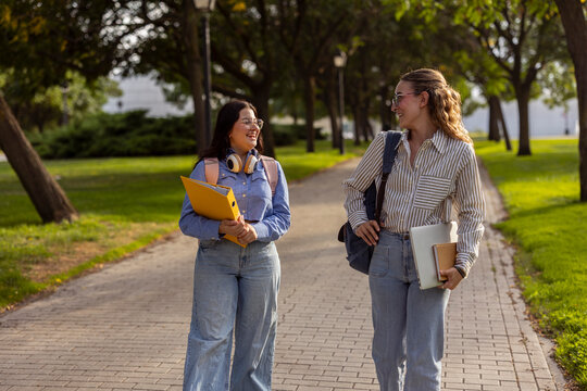 Two female students walking on campus and talking outdoors