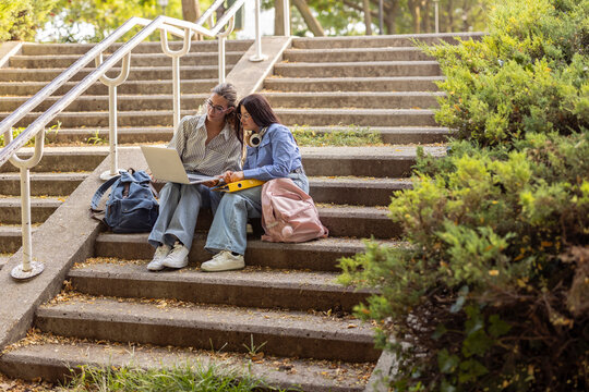 Two female friends studying together outdoors on campus steps