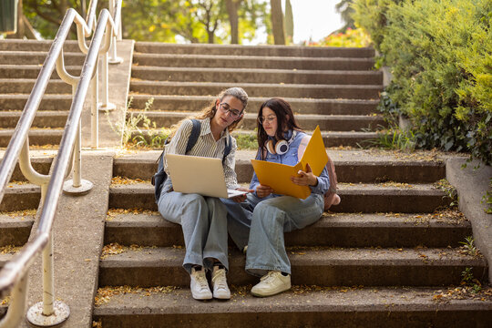 Two women friends students studying on outdoor campus steps