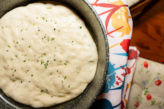 Sourdough focaccia dough rising in pan with herbs