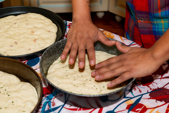 Hands shaping sourdough focaccia dough in home kitchen