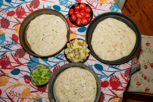 Homemade sourdough focaccia dough in pans with toppings