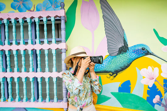 Traveler photographing colorful mural in Guatape, Colombia