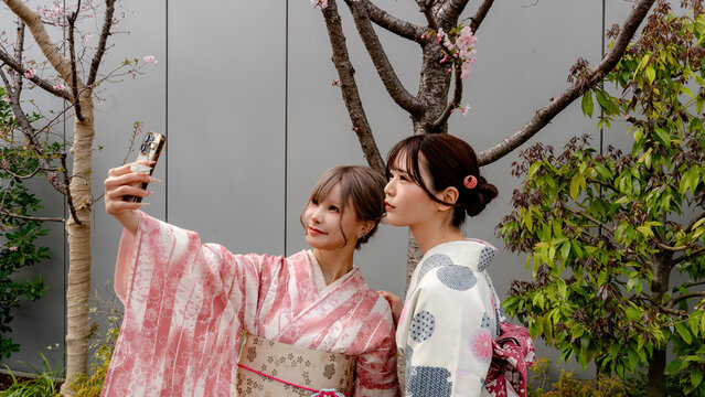 Japanese women in kimono taking selfie under sakura, Tokyo
