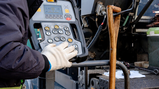 Worker operating asphalt paving machine controls