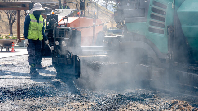 Workers laying fresh asphalt for smooth street paving