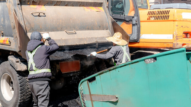 Asphalt paving operation with workers repairing street