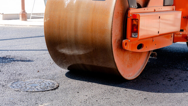 Asphalt roller compacts fresh pavement on city street