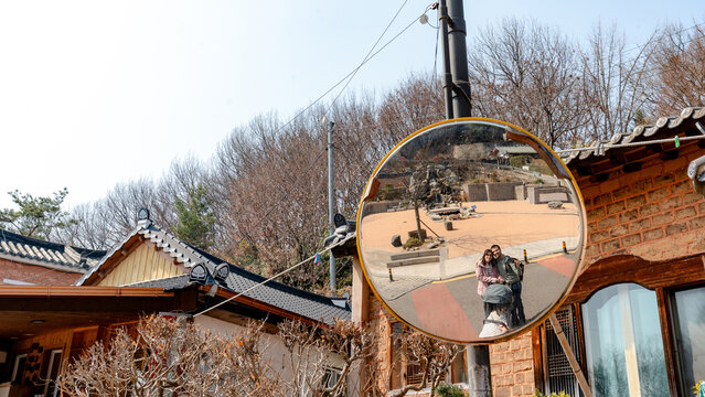 Convex road mirror reflection of family in Jeonju street