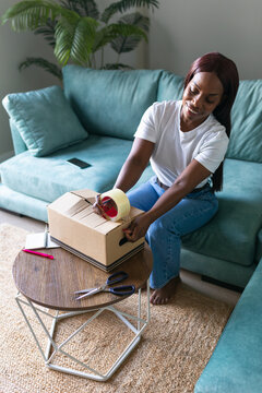 Black woman packing sold item for secondhand app shipping