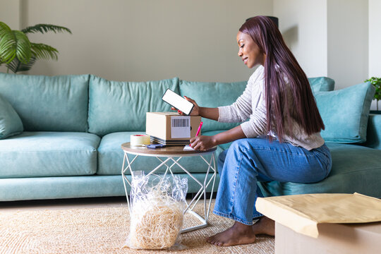 Black woman listing a secondhand item online from home