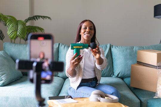 Black woman recording secondhand app listing from home