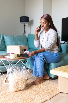 Woman calling courier and checking shipment at home
