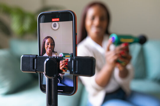Black woman recording secondhand app listing from home