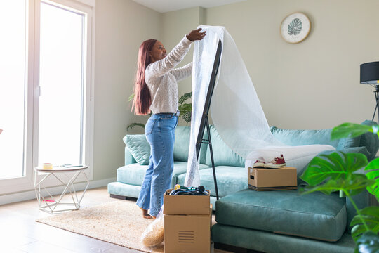 Black woman packing secondhand mirror with bubble wrap