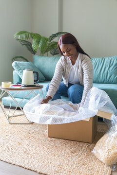 Black woman unboxing secondhand purchase from resale app at home