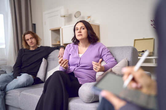 Concerned couple attending therapy session in bright living room