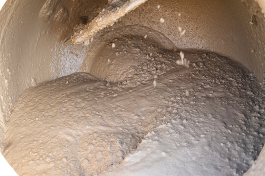 Closeup of wet concrete mix inside rotating cement mixer drum