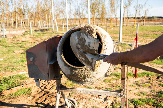 Concrete worker loading mixer at outdoor construction site