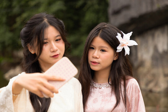 Young Vietnamese teenagers take selfie in traditional dress by temple