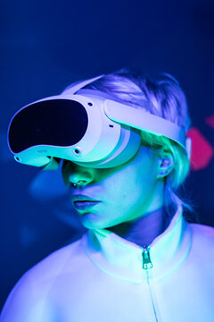 Futuristic woman wearing VR headset in neon light portrait