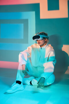 Futuristic woman wearing VR headset in neon light studio