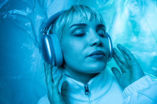 Futuristic woman listening to music in blue neon light