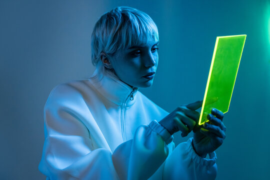 Futuristic woman using neon tablet in blue light studio