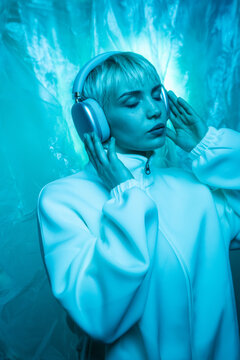 Futuristic woman in blue light wearing headphones, serene