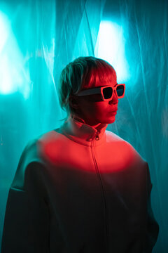 Futuristic woman in neon light with sunglasses and jacket