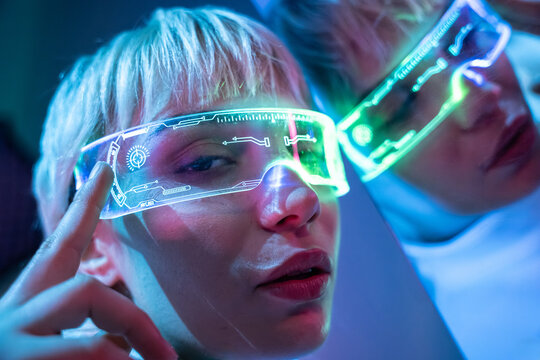 Futuristic woman with holographic visor in neon light