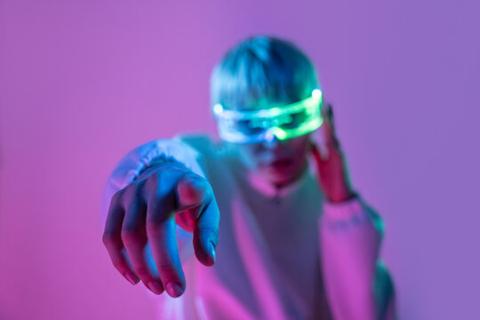 Futuristic woman in neon visor reaching toward camera