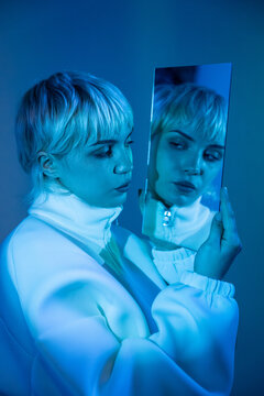 Futuristic woman with mirror reflection in blue neon light