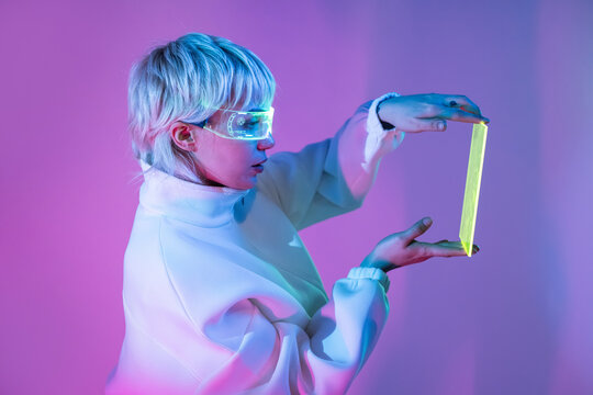 Futuristic woman in neon goggles holding a glowing frame