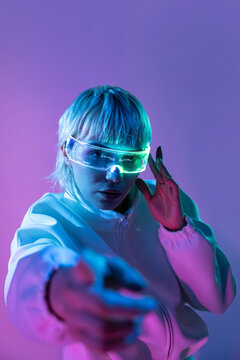 Futuristic woman in neon light wearing glowing visor glasses