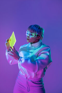 Futuristic woman examining glowing panel in neon light