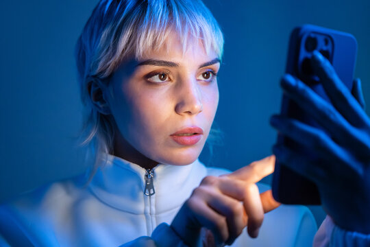Futuristic woman using smartphone in blue neon light