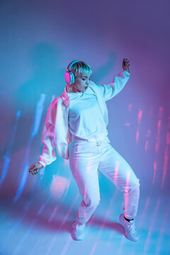 Futuristic woman dancing with headphones in neon light