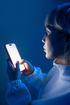 Futuristic woman using glowing smartphone in blue light