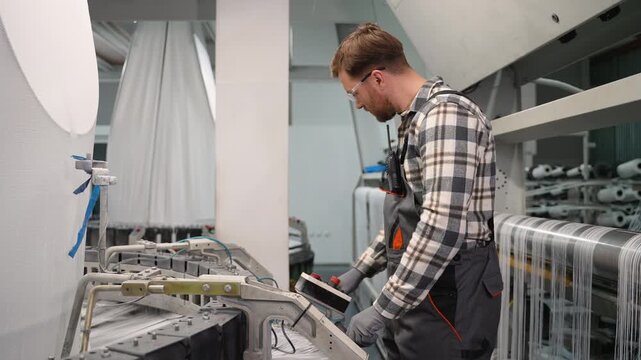 Male factory worker operating industrial polypropylene production machine