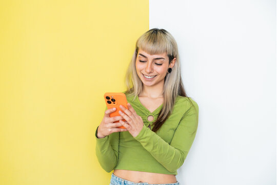 Smiling young woman using a smartphone on color background