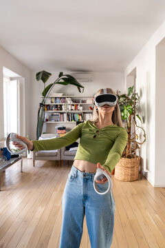 Woman using VR headset and controller in bright home living room