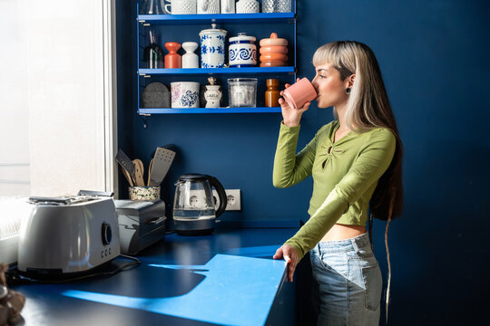 Young woman drinking coffee in a modern home kitchen