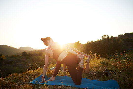 Women doing yoga on a hill at sunrise in nature