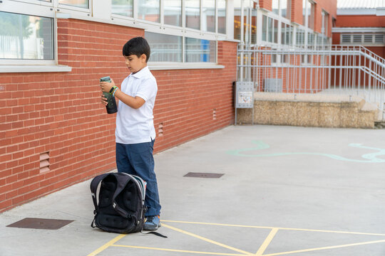 Boy holding a bottle outside school building