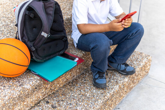 Young boy with backpack and basketball at school